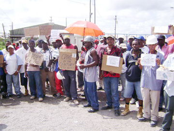  Striking Bosai workers picketing outside the bauxite plant at Linden yesterday with their placards. 