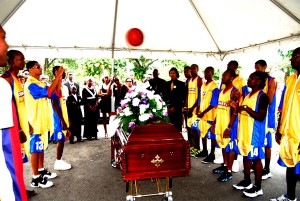 The final pass! Players of the Courts Pacesetters Basketball Club toss a basketball over the body of Kevin Worrell who passed away last Saturday  in a knock-out competition at the outdoor Burnham basketball Court. (Lawrence Fanfair photo)  