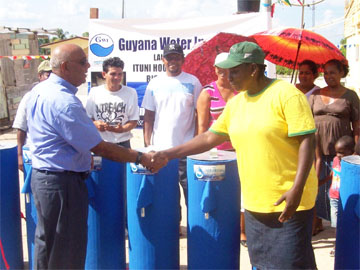 Chief Executive of GWI, Karan Singh (left) symbolically handing over the filters to Olvet George, the GWI Water Service Operator in Ituni. 