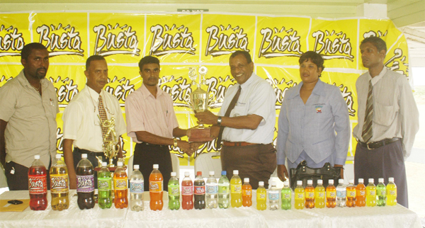 Secretary of the Georgetown Cricket Association (GCA) Shalim Baksh accepts the trophy from Managing Director of Guyana Beverage Company Robert Selman, in the presence of other GCA and GBC officials. (Aubrey Crawford photograph)  
