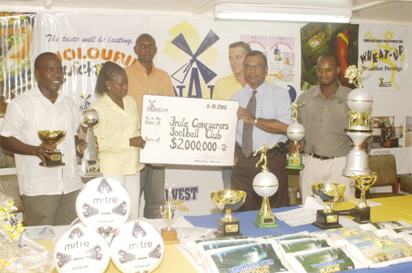 Managing Director of NAMILCO  Bert Sukhai (2nd R) hands over a cheque for $2M to the secretary of Fruta Conquerors Fruta Conquerors in the presence of the President of the FC Marlan Cole (L), Managing Director of Soccerama Mark Bradford (3rd), Marketing Manager Damon Pistano  (far R) and Operations Manager Ralph Hemsingh (3rd R). (Aubrey Crawford photo).  