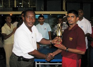 Neal and Massy captain Harold Baboolall (right) receives the Winning Trophy from Banks DIH Executive Trevor Nero.  