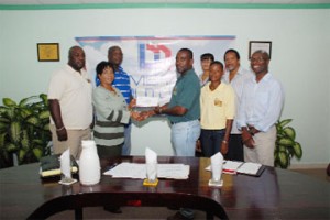 Demerara Mutual Life Public Relations Manager Marjorie Chester hands over a cheque to GRFU Senior Vice President Robin Peters while GRFU and Demerara Mutual members look on. (Clairmonte Marcus photo)  