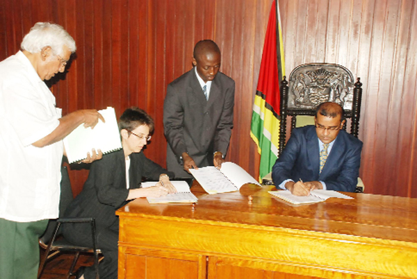 President Bharrat Jagdeo (right) signing the supplement and addendum to Esso’s Prospecting Licence at the Office of the President yesterday.  Jagdeo affixed his signature on behalf of the government while Area Manager of Esso Exploration and Production (Guyana) Limited, Jan-Claire Phillips (also sitting), signed on the company’s behalf.   
