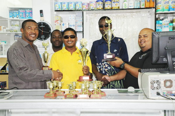 (President and Public Relations Officer of the Yamaha Caribs Rugby Football Club (YCRFC) Charles Greaves (left) and Troy Yhip (right) receives the sponsorship trophies from Robert Persaud of Roberts Jewellery (second left) and Paul Mollyneaux Sports organizer Mike’s Pharmacy (second right) respectively. Standing somewhat  behind Robert Persaud is Yamaha Caribs club member Gregory Wills.  