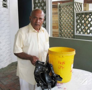 Francis Gonsalves displays the bucket that helped to keep his sister, Sherry Haynes alive and a bag belonging to their sister Sheila Gonsalves. 