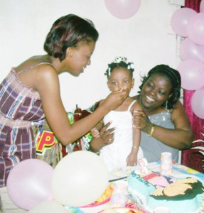 Two-year-old Akeriah braces against her cousin Mandisa Breedy as her mother Akila Jacobs feeds her cake on her second birthday in February.  