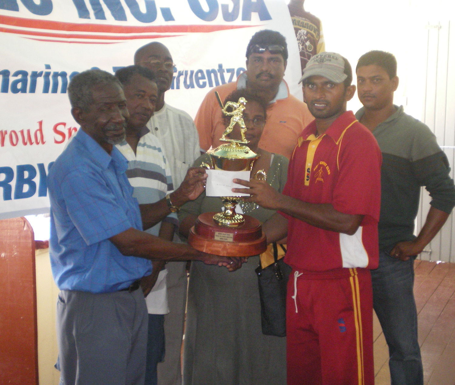 Albion Community Centre captain Sewnarine Chattergoon receives the TENELEC INC championship trophy from former president of the Berbice Cricket Board of Control (BCBC) Malcolm Peters while other BCBC officials look on.