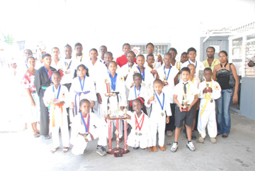 The successful Harpy Eagles team poses with the prizes they won at the Third National Open Karate Championships on Sunday at the Diamond Community Centre Building, EBD. Harpy Eagles coach/Sensei Troy Bobb stands second from right along with other parents and supporters of the club. (Clairmonte Marcus Photo) 