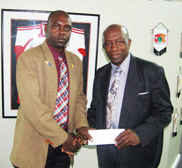 FIFA Vice President Austin Warner handing over a letter of commitment to Aubrey ‘Shanghai’ Major at the Marvin Lee Stadium on Wednesday.  