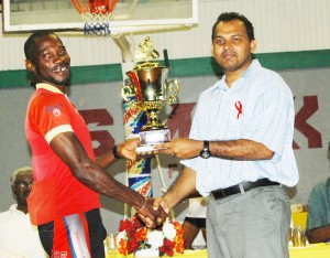 Overall winner Junior Niles is all smiles as he collects the first place lien trophy from Minister of Sports Dr. Frank Anthony at the Cliff Anderson Sports Hall yesterday.(Lawrence Fanfair photo) 