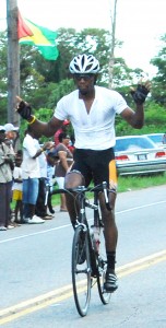 ‘Marlon ‘Fishy’ Williams raises his arms in triumph after claiming the fifth stage of the second annual ‘Riding for Life’ cycle road race yesterday morning from Kara Kara in Linden to Homestretch Avenue. (Photograph by Lawrence Fanfair)