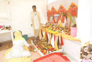 Pandit Hardat Ramkarran and a devotee performing a Hawan yesterday at the mini-altar on the East Coast Demerara yesterday in observance of Kartik Nahan. (See story on page 17) (Photo by Jules Gibson) 