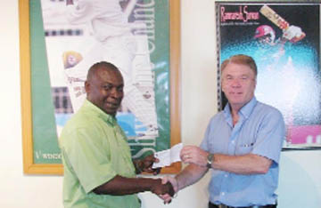 Troy Peters of the `Reds’ Perreira Foundation hands over the  sponsorship cheque to David Burgess, honorary member of the Rose Hall Town Youth and Sports Club.    