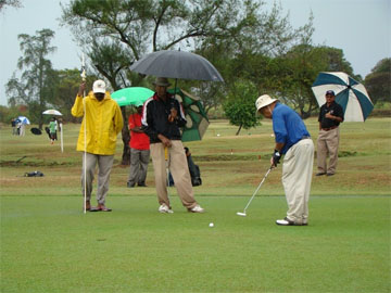 Players braving the rain on the opening day of the Smirnoff Guyana Open golf championships at the Lusignan Golf Club yesterday.   