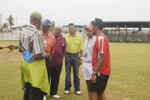 All Washed Out! Match Referee, Grantley Culbard (second left) points to the pitch as he briefs the two captains Daren Ganga, right and Sunil Dhaniram second right on the position. Others in picture are umpires Clyde Duncan, far left, Daveteerth Anandjit, centre and Clancy Mack on Anandjit’s right. (Aubrey Crawford photo)   