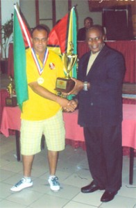 DOMINO KING! Guyana’s Gary `Tie Tongue’ Jansen proudly receives his King Domino trophy for being the number one player in the World Council of Domino Federations (WCDF) championships. Jansen was also voted the Most Outstanding Player at the championships which were held last month in Antigua. 