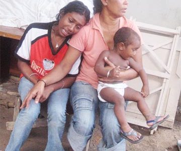 Deep grief: Latchman Persaud’s wife, Swarsattie Etwaroo (left) being consoled by his mother Kalrani, who holds the couple’s one-year-old son Jonathan. Persaud called ‘Boyo’ was stabbed to death on Sunday a few corner from his Better Hope home. (Photo by Brenon Sukram) 