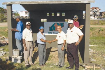 TCL General Manager Satnarine Bachew hands over the bus shed - under construction- to NDC Chairman Cecil Ramdat, TGI Plant Manager Mark Bender and TGI PR  Consultant Alex Graham look on