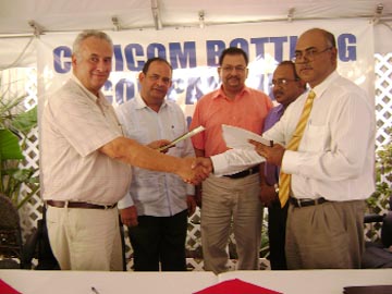 Joshua Safeek (right)of Safeco Group of Companies shakes hands with Emani Rodriguez (left) of Venezuelan company Mundial Maquinas CA after signing the deal yesterday. Standing in the background from left are Venezuelan Ambassador Dario Morandy; Geoff DaSilva of Go-Invest (centre) and Saisnarine Kowlessar (partly hidden).