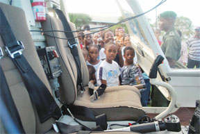 Children crowd around the Bell 206 Ranger helicopter at Camp Ayanganna on Friday. (Photo courtesy of the GDF)