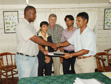 The contract to build the guesthouse and wardens’ quarters at Tukeit in the Kaieteur National Park was signed yesterday at the National Parks Commission Boardroom. Contractor Aubrey Changlee (left) receives the contract from Chairman of the Kaieteur National Park Board Shyam Nokta (right). Also in photo are General  Manager National Parks Commission Yolanda Vasconcellos, Consultant Ben Ter Welle, and Environmental Officer of the EPA Oumardatt Ramcharran. (Photo by Jules Gibson)