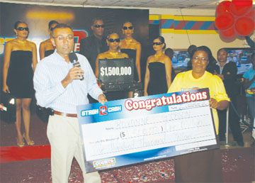 Roxanne Gibson (right) is the latest winner in the Courts Stash of Cash Christmas promotion. Here she savours the moment and collects her $1.5M prize from Courts (Guyana) Inc, Manager Lester Alvis. The weekly contest to pick the briefcase with the most money in it was held yesterday.  