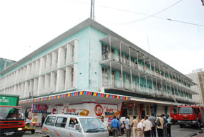 Fire-fighters and police officers at the scene of the fire at the Guyana Post Office Corporation building yesterday.  