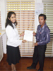 Director of the Wildlife Division Alona Sankar hands over the ornamental fish licences to toshao of Rockstone Rance Alicock.  