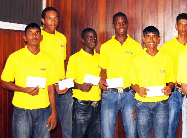 GCA president Bishwa Panday (right) presents captain of the Guyana Under-17 team Dexter Solomon with his stipend  while his teammates look on in appreciation. (Lawrence Fanfair photograph). 