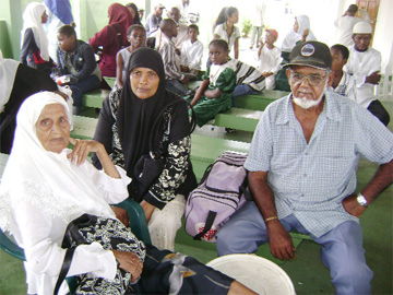 Yesterday Muslims turned up at their respective mosques to celebrate Eid ul Adha. In this photo, Abdool Kaleem Razack (right) sits at the East Zanitul Mosque in Prashad Nagar with his relatives, Bibi Nazmoon Nesha and Bibi Rhaira Baksh. The trio was among other members who had gathered to watch the sacrifice of 14 cows and to collect some of the beef after a portion had been shared out to the persons waiting outside. This newspaper was told that 1/3 of the meat is kept for members of the mosque while the remainder is shared out to friends and those in need. A member of the Municipal Food & Hygiene/Abattoir was on hand to oversee the exercise.   