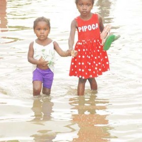 These girls were wading through the floodwaters at Main Street, Ann’s Grove yesterday. (Jules Gibson photo) 