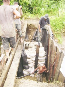 Mud bags and wood: Employees work to fix the breach at Middlesex, Essequibo on Thursday.   