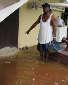 Samuel Anthony places sand at his door to prevent the water from entering his bottom flat. 