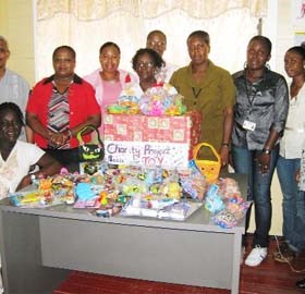 Staff posing with some of the gifts that would be distributed to the children; standing second from right is Camille Reid and fourth from right is Merlyn Henry.                 