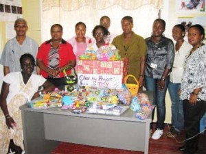 Staff posing with some of the gifts that would be distributed to the children; standing second from right is Camille Reid and fourth from right is Merlyn Henry.                 