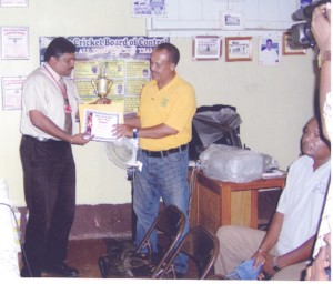 Treasurer of the Berbice Cricket Board of Control (BCBC) Anil Beharry hands over the certificate and trophy to Hubern Evans.  