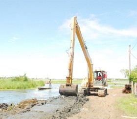 Damming Dochfour: An excavator at work yesterday building up a dam at Dochfour, East Coast Demerara, over which residents hope to pump the foetid floodwater that has been lingering in the village for some 16 days. (Photo by Jules Gibson)  
