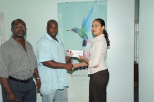 Mr. Guyana Mark Anthony Perry (left) receives his two airline tickets from Caribbean Airlines Sales Executive Kathleen Shuffler-Ten-Pow, whilst GABBFF president Frank Tucker looks on appreciably. (A Clairmonte Marcus photograph)     