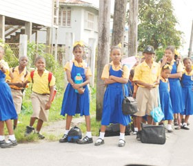 Road safety? Pupils of the West Ruimveldt Primary School stand at a corner near their school awaiting transportation to get home yesterday. A sign that the authorities should address the demarcating of bus stops near schools to prevent this dangerous practice. (Photo by Jules Gibson) 