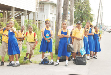 Road safety? Pupils of the West Ruimveldt Primary School stand at a corner near their school awaiting transportation to get home yesterday. A sign that the authorities should address the demarcating of bus stops near schools to prevent this dangerous practice. (Photo by Jules Gibson) 