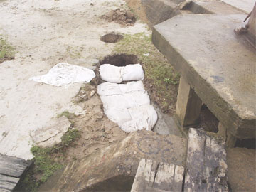 A section of the earthen embankment close to the seawall which has caved in. Sandbags have been put in as a temporary measure but the erosion continues. The other smaller hole appears to have been deliberately dug.  