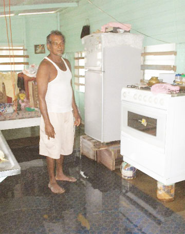 Saywack Ramjewan stands in the kitchen which still has about an inch of water. Household appliances had to be elevated in an effort to prevent them from being damaged by the water. 