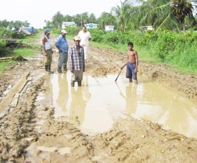 Alim Khan (left) and a youth standing in the “pond” on the dam as other residents look on. 