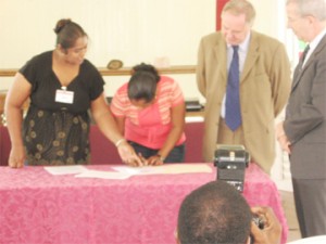  High Commissioner Charles Court  (second from right) , Head of Development (CIDA) Raymond Drouin (right) and Chairman of Airy Hall Development Group Bidiawatie Persaud look on as Project Coordinator Kumarie Mohamed signs the agreement. 