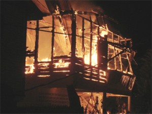 The completely engulfed home of Krishna and Parbattie Persaud in which they and their two grandchildren died in the wee hours of yesterday. 