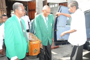  First class umpire Clyde Duncan (second right) and president of the Georgetown Cricket Umpires Council (GCUC) Grantley Culbard (left) lead the pall bearers bearing the body of their former colleague Compton Vyphuis. (Clairmonte Marcus photo) 