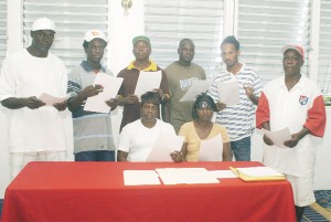 From left (standing): Clyde Williams, Cecil Smith, Clifford Griffith, Leon Gilkes, Jermaine King, Cecil Alfred and sitting Sharon Warde and Veronica Blackman display their contracts after affixing their signature on the dotted line at the Main Street Plaza Hotel yesterday. 