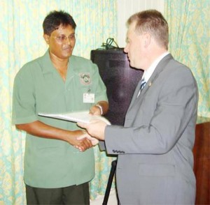 James Singh, Commissioner of Forests (left) receiving a signed copy of the agreement from Dominick Plouvier, Director WWF, Guyana. (Ministry of Agriculture photo) 