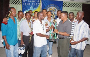 BFA’s president, Keith Ojeer, right, presents the trophy to captain of the Corriverton Links and the tournament’s highest goal scorer, Albert Anderson, while other BFA members and footballers are in the background.